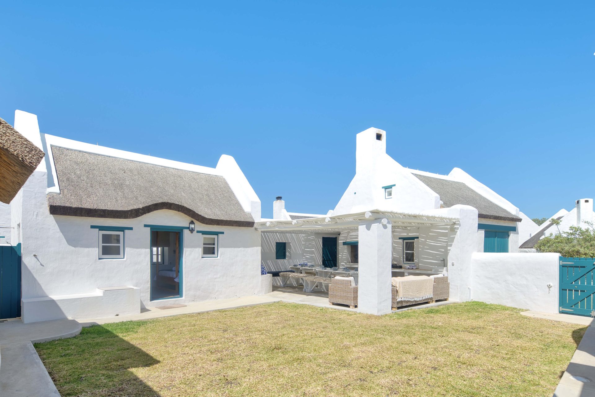 The whitewashed thatched cottages of Cape Creek Retreat around the courtyard lawn