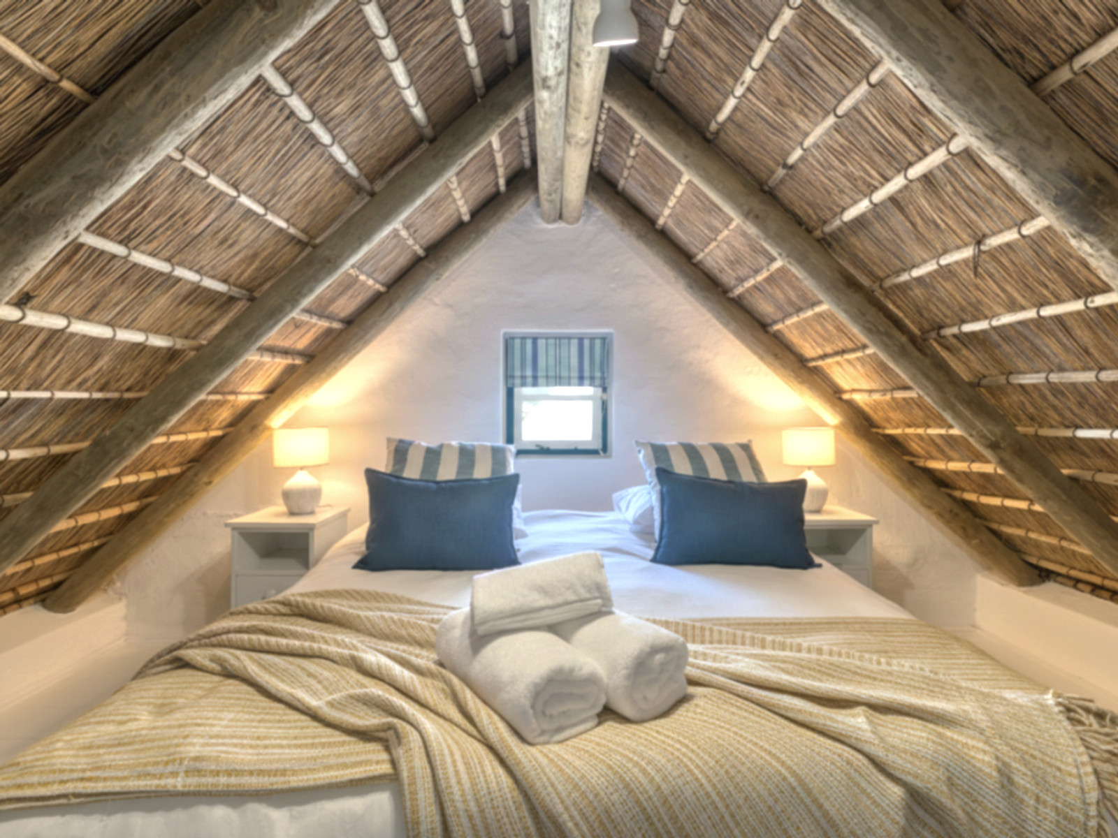 The Oystercatcher Loft at Cape Creek Retreat, lamps either side beneath the thatch