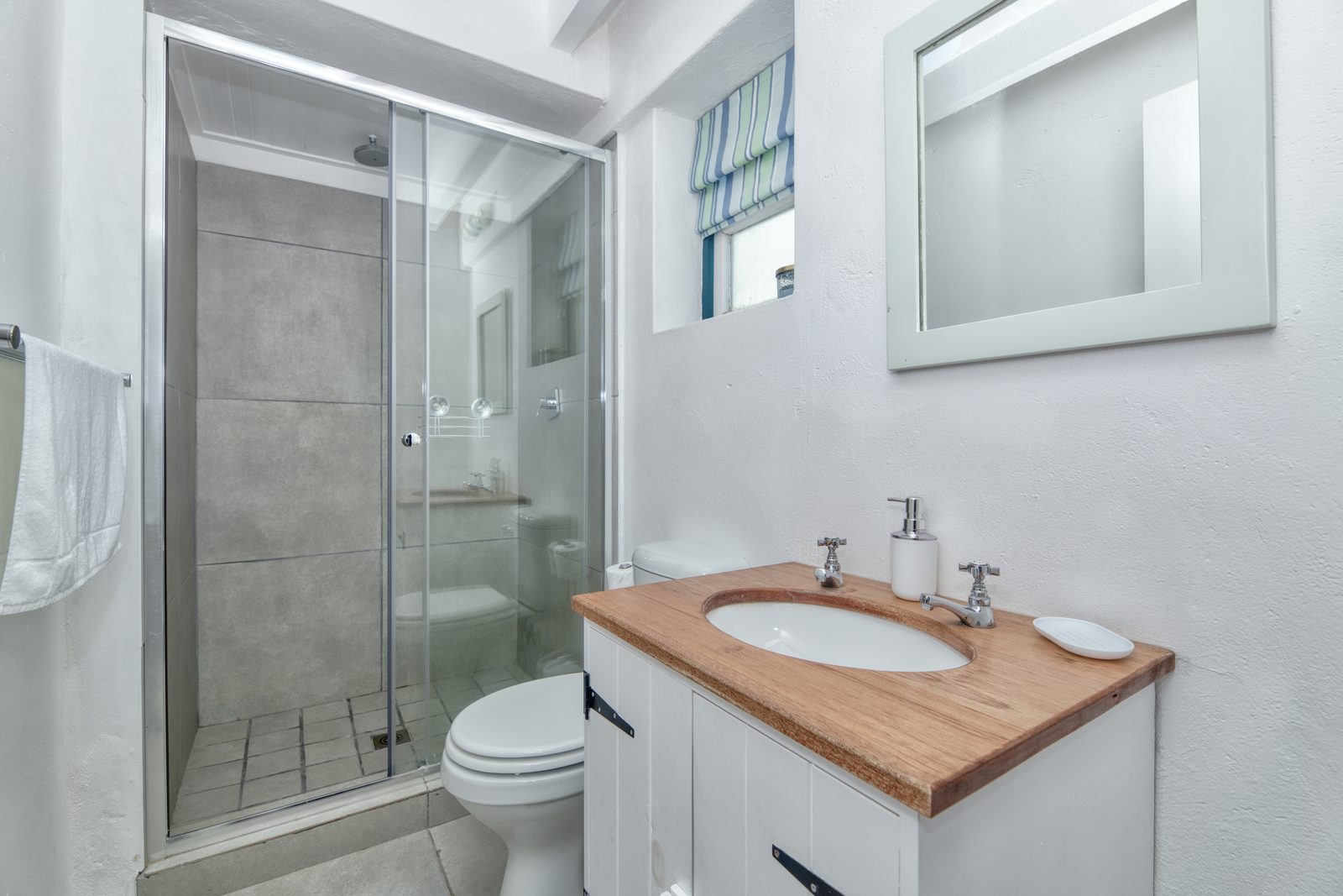 The shared main-house bathroom at Cape Creek Retreat, its shower cubicle beside the timber-topped vanity